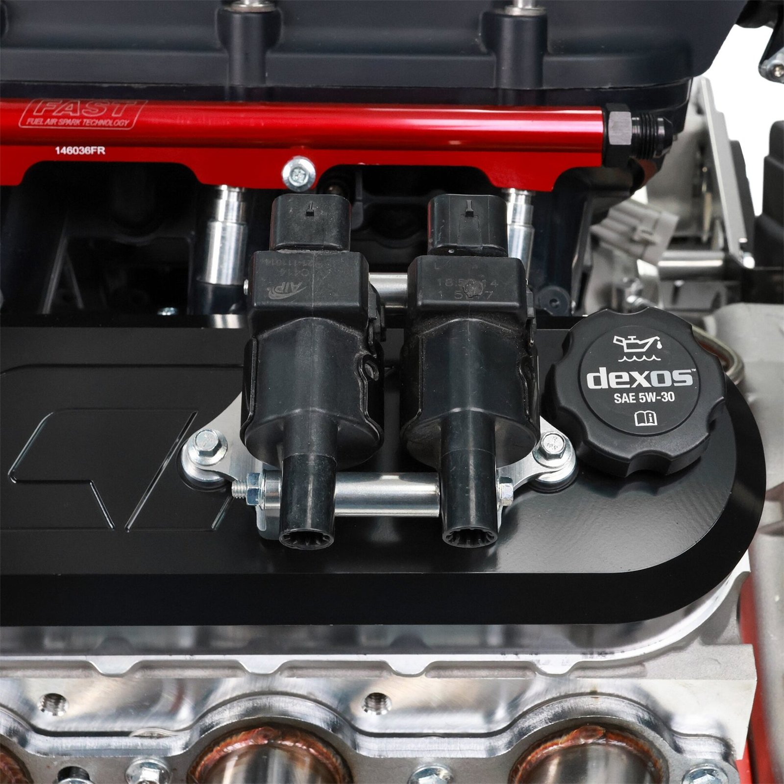 Two ignition coils bolted into ICT Billet's new coil brackets on a black ICT billet LS valve cover, close up