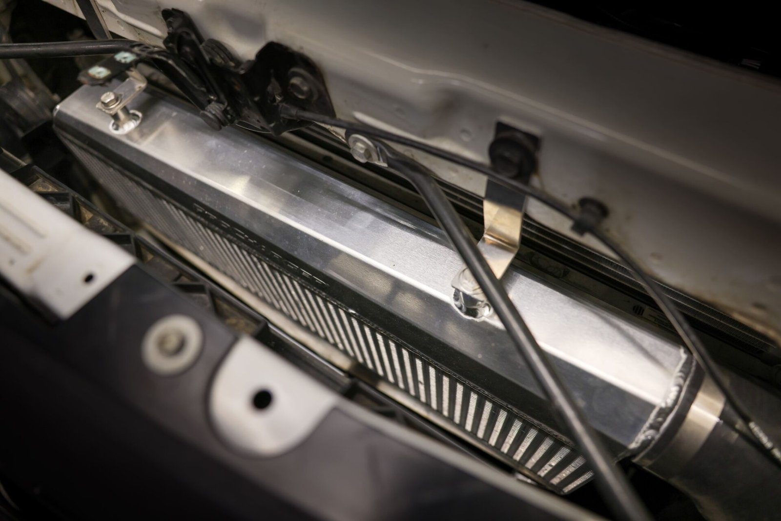 ProCharger's new, larger air-to-air intercooler mounted behind the grille of a white GM truck