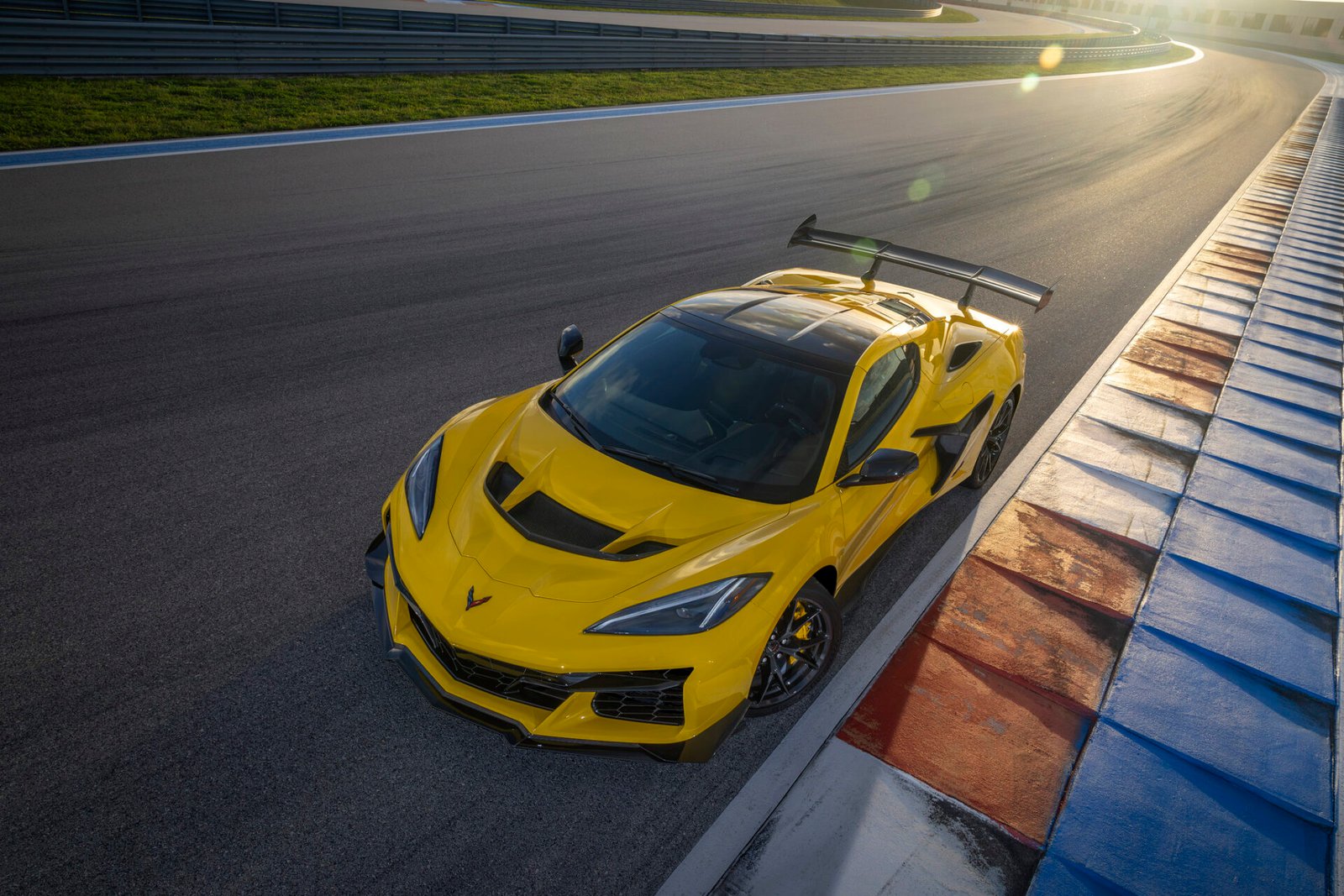 Yellow Chevrolet Corvette ZR1 coupe with its high wing, seen from above at the front on track at sunset